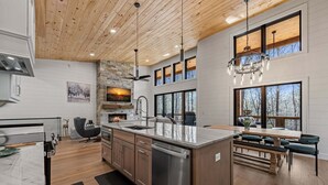 Una cucina moderna con una grande isola, soffitto in legno e ampie finestre.