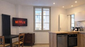 Eine moderne Küche mit Geschirrspüler, Backofen und einer Holzarbeitsplatte. An der Wand ist ein Fernseher angebracht, der das Netflix-Logo zeigt.