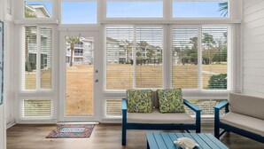 Et værelse med udsigt over en strand og huse, med en blå sofa og et lille bord.