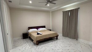 Ein Schlafzimmer mit Bett, Deckenventilator und einem Fenster mit Vorhängen.