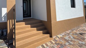Ein Gebäude mit einer beigefarbenen und weißen Fassade, einer schwarzen Tür und einer Treppe, die zum Eingang führt.