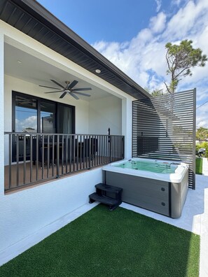Un espace extérieur moderne doté d’un jacuzzi, d’une pelouse artificielle, d’un balcon avec un ventilateur de plafond et d’une pergola.
