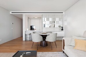 A modern living room with a dining area, featuring a sofa, a coffee table, and a dining table with chairs.