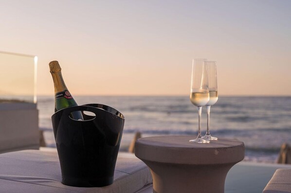 A bottle of champagne and a glass on a table by the ocean. - Marika Hotel Chania (Platanias)