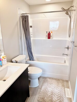 A modern bathroom with a bathtub, toilet, and sink. - The Luxe Haven S - Luxury 3BR | 2.5BA Family Home • Stylish • Serene (Calgary)