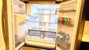An open refrigerator with shelves and a freezer compartment, and a microwave above it. - The Luxe Haven S - Luxury 3BR | 2.5BA Family Home • Stylish • Serene (Calgary)