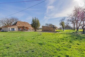 Uma propriedade rural com uma casa grande, um celeiro e campos gramados extensos.