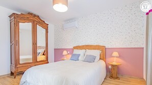 A bedroom with a large wooden wardrobe, a bed with white bedding, two bedside lamps, and floral wallpaper. - Cosy Bresse - SAINT VINCENT EN BRESSE (SAINT VINCENT EN BRESSE)