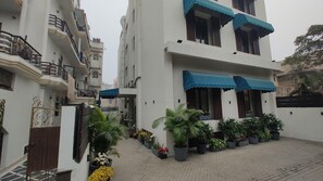 A multi-story residential building with balconies, potted plants, and a gated entrance. - Saltstayz Thyme (New Delhi)