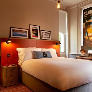 A hotel room with a large bed, a nightstand, a framed picture, and a poster on the wall. - Bike & Boot Inns Scarborough - Leisure Hotels for Now (Scarborough)