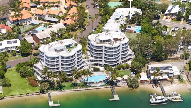 Un resort con diversi edifici circolari, una piscina centrale e una spiaggia con barche.