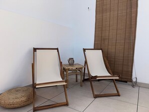 Two wooden lounge chairs with white cushions, a woven round cushion, and a small table with a lantern. - NEW - Old Town Modern Apartment Close to Beach (Estepona)