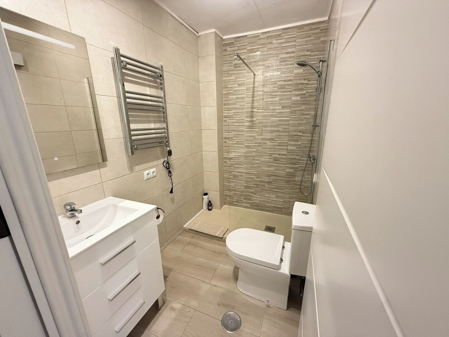 Une salle de bain moderne avec un meuble-lavabo blanc, une cabine de douche en verre et des toilettes.
