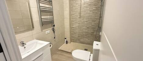 Une salle de bain moderne avec un meuble-lavabo blanc, une cabine de douche en verre et des toilettes.