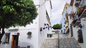 Une rue étroite bordée de bâtiments blancs, d’escaliers en pierre et de plantes en pot.