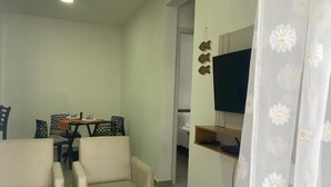 A living room with two sofas, a dining table with chairs, a TV mounted on the wall, and a curtain with a floral pattern. - Durei Refuge: Ideal for remote work with fast Wi-Fi! (Paraty)