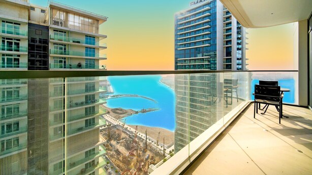 Un edificio alto con vista su una zona costiera, che include un porto turistico e un grande edificio con la scritta "FMAAR".