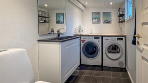 A compact laundry room with two front-loading washing machines, a sink, and a mirror.