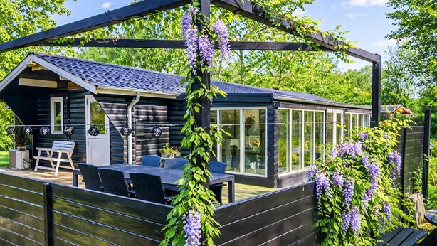 A wooden deck with a glass-enclosed patio, a wooden bench, and a table with chairs.