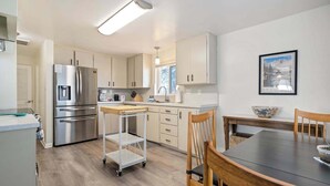 Een moderne keuken met roestvrijstalen apparatuur, een houten eettafel en uitzicht op de omgeving.