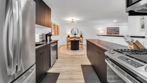 A modern kitchen with a central island, stainless steel appliances, and a dining area with a round table and chairs.