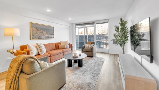 A modern living room with a sofa, armchair, coffee table, and a TV mounted on the wall.