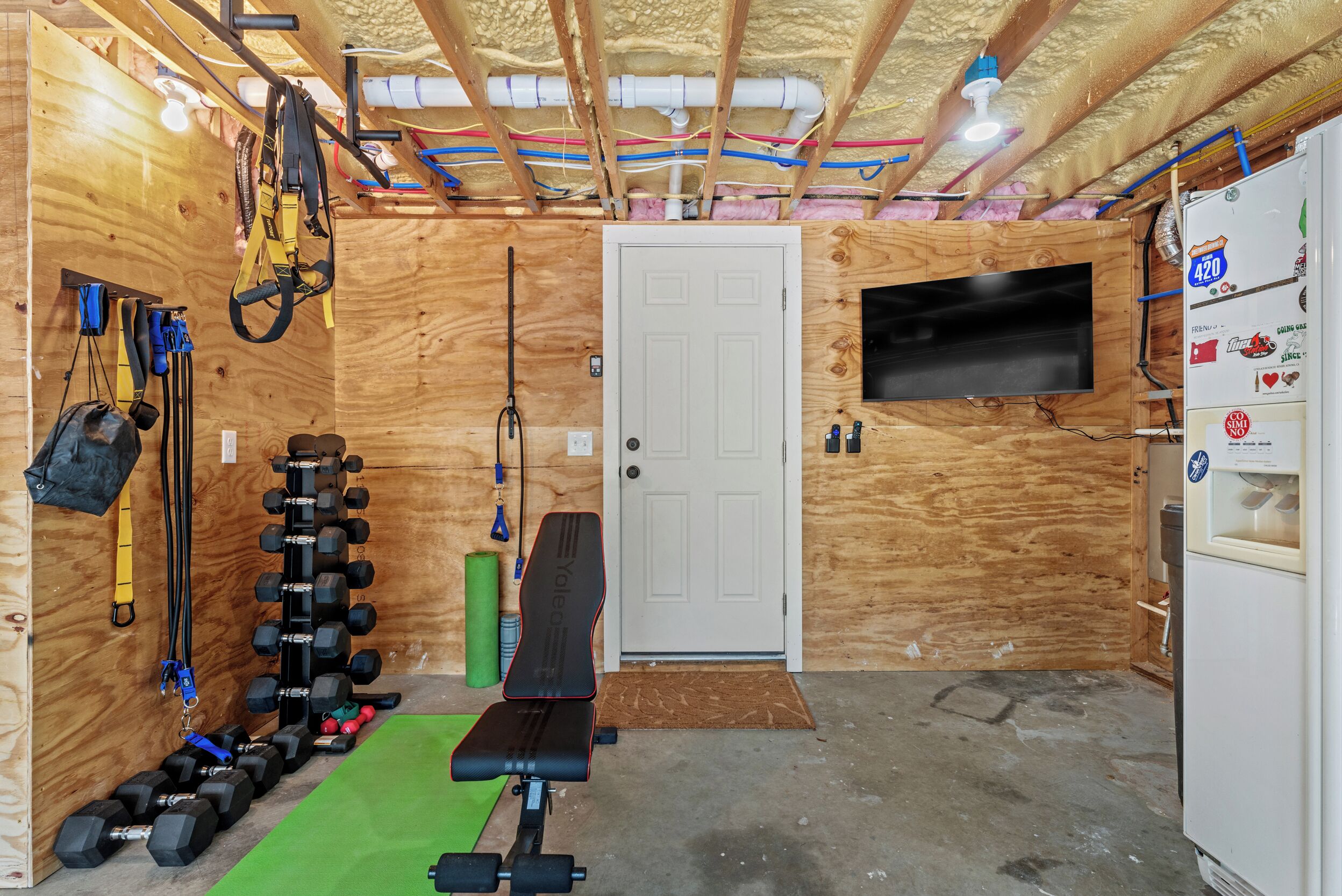 Une salle de sport équipée d’un banc, d’haltères, d’élastiques de résistance et d’un tapis de course.