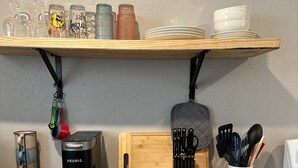 En köksbänk med en Keurig-kaffemaskin, en skärbräda, ett knivställ och diverse köksredskap.
