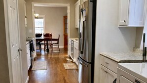 Une cuisine avec un plancher en bois, des armoires blanches, un réfrigérateur en acier inoxydable et un lave-vaisselle.
