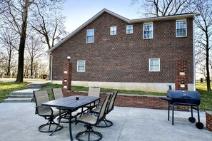 A brick house with a patio, outdoor seating, and a grill.