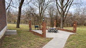 Un espace patio agrémenté d’un mur en briques, d’un chemin en béton et d’une table avec des chaises.
