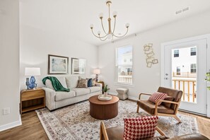 A living room with a sofa, armchair, coffee table, and a chandelier.