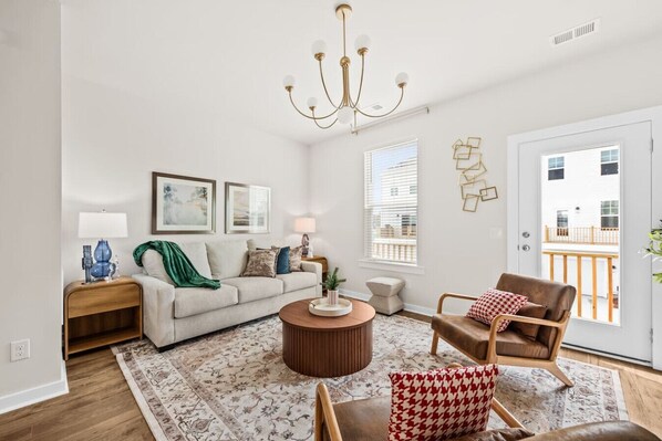 Una sala de estar con sofá, sillón, mesa de centro y candelabro.