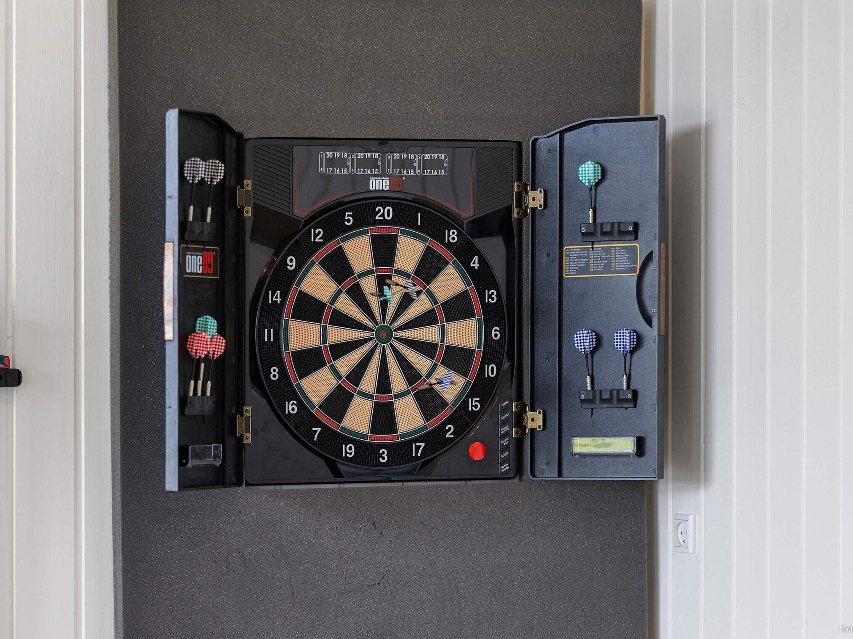 Un jeu de fléchettes fixé au mur, avec un étui à fléchettes à côté.