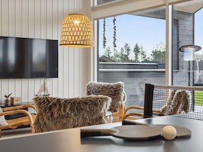 A modern living room with a television, a hanging light fixture, and a view of the outdoors. - 5 Star Holiday Home in Bogense (Bogense)