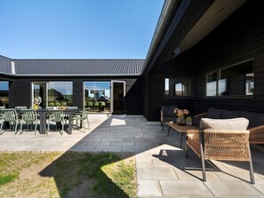 Um pátio moderno ao ar livre com área de jantar, assentos e vista para o edifício vizinho.