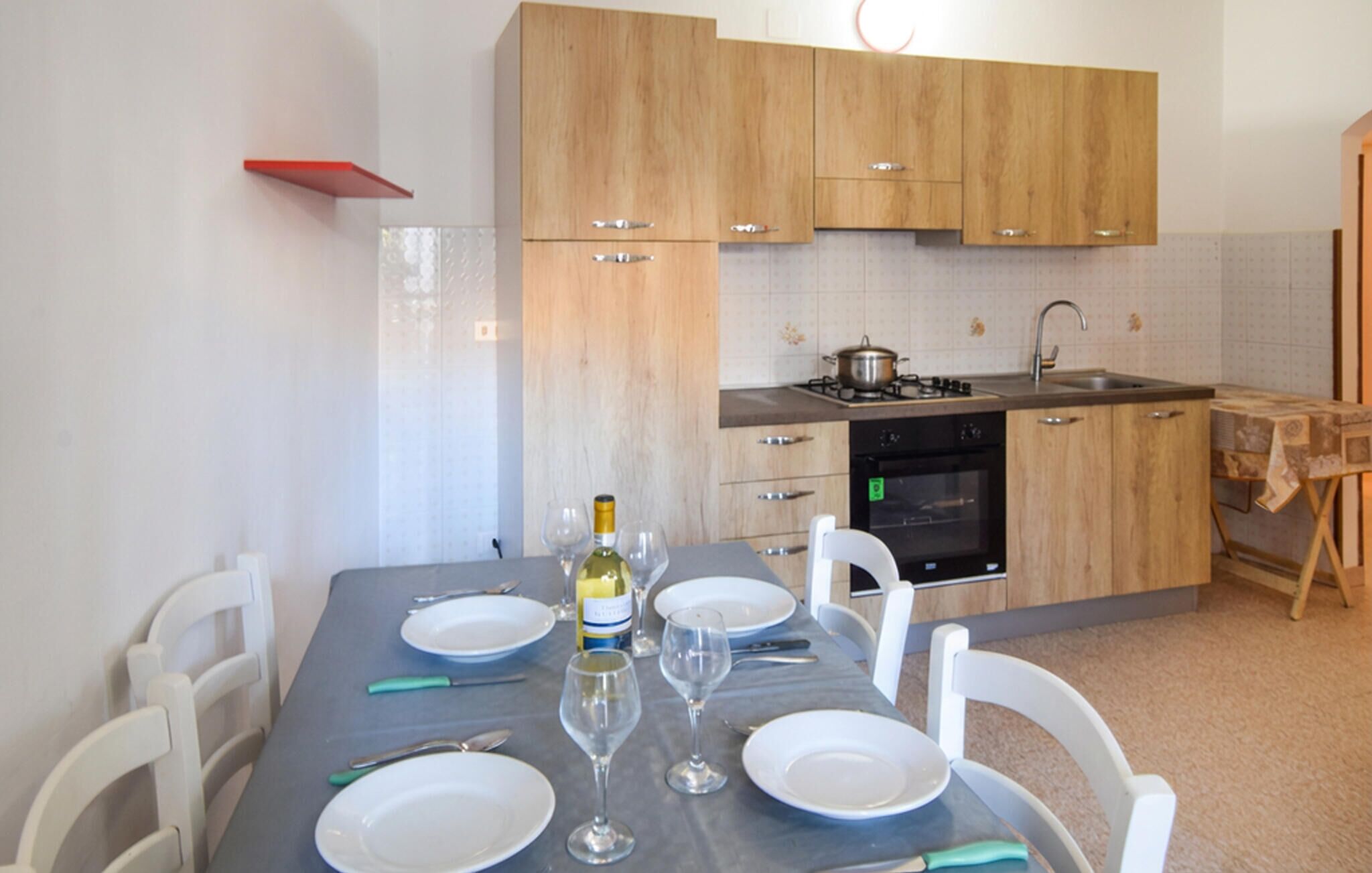 A kitchen with wooden cabinets, a stove, and a dining table set for four.