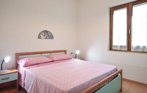 A bedroom with a bed, bedside tables, a lamp, a wall decoration, and a window with curtains. - 2 bedroom lovely home in Punta Licosa (Punta Licosa)