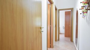 Passadís amb portes de fusta, sòl de rajola i un ventilador penjat a la paret.