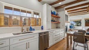 Una cocina moderna con armarios blancos, electrodomésticos de acero inoxidable y vigas de madera en el techo.