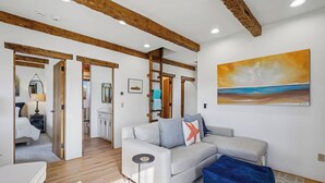 Una sala moderna con un sofá, un reposapiés azul y un cuadro en la pared.