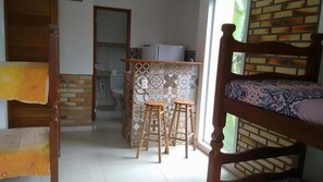 A room with a bed, a small kitchen area with a refrigerator, and a bathroom visible through an open door. - Pousada Vista da Barra (Florianópolis)