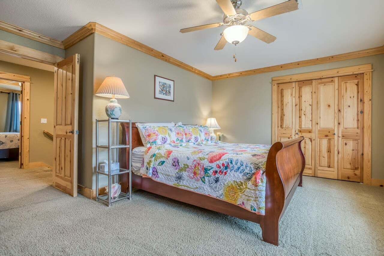 Ein Schlafzimmer mit einem hölzernen Bett, einem Deckenventilator, einer Lampe und einem Kleiderschrank.