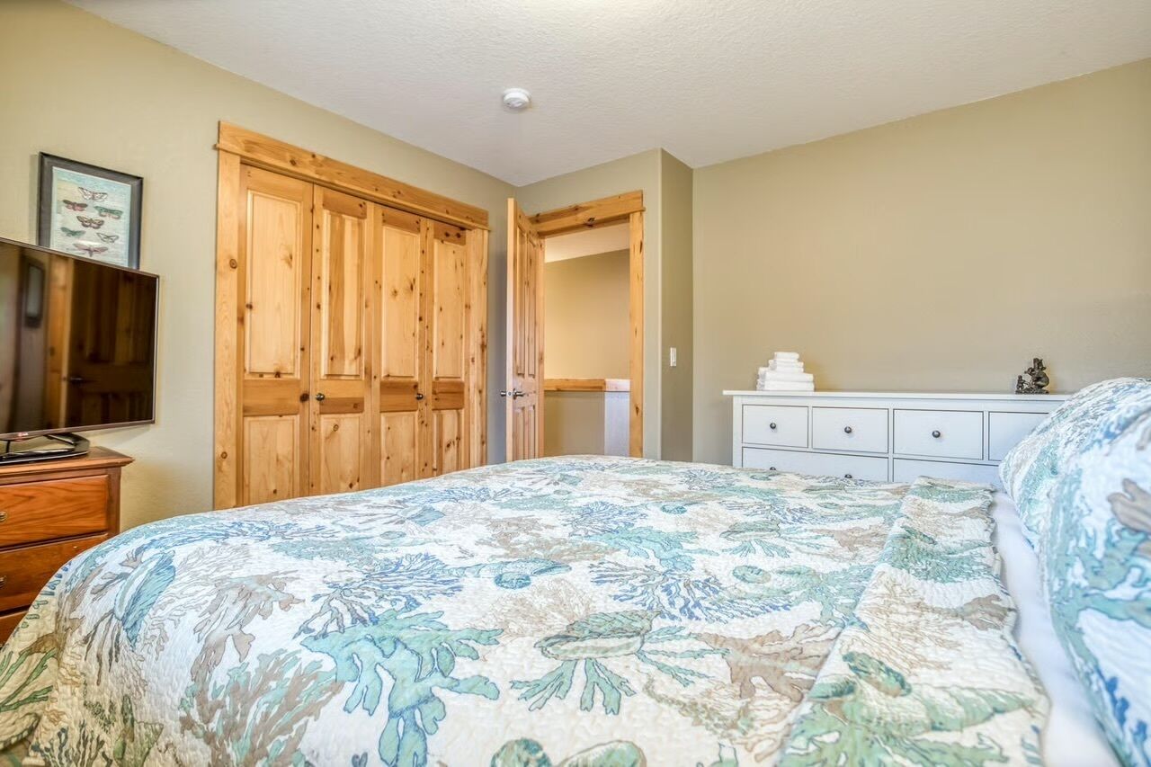 Een slaapkamer met een bed, een houten garderobe, een dressoir en een ingelijst schilderij aan de muur.