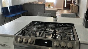 Une cuisine moderne dotée d’une cuisinière en acier inoxydable, d’une horloge numérique et d’un élégant pare-feu.