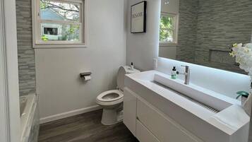 Ein modernes Badezimmer mit Toilette, Waschtisch und Fenster.