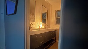 Ein modernes Badezimmer mit einem Doppelwaschtisch, einem Spiegel und Einbaustrahler.