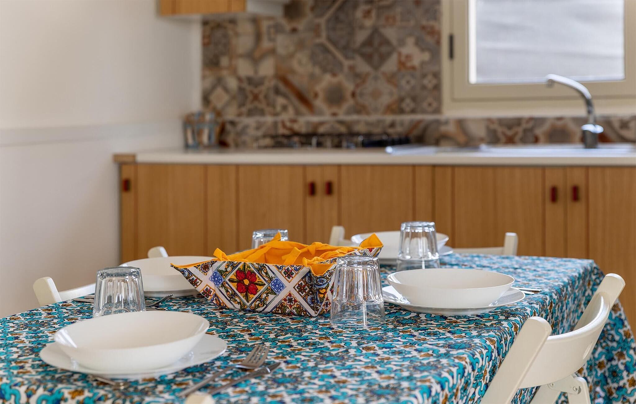 A dining table set with plates, glasses, and a colorful napkin holder.