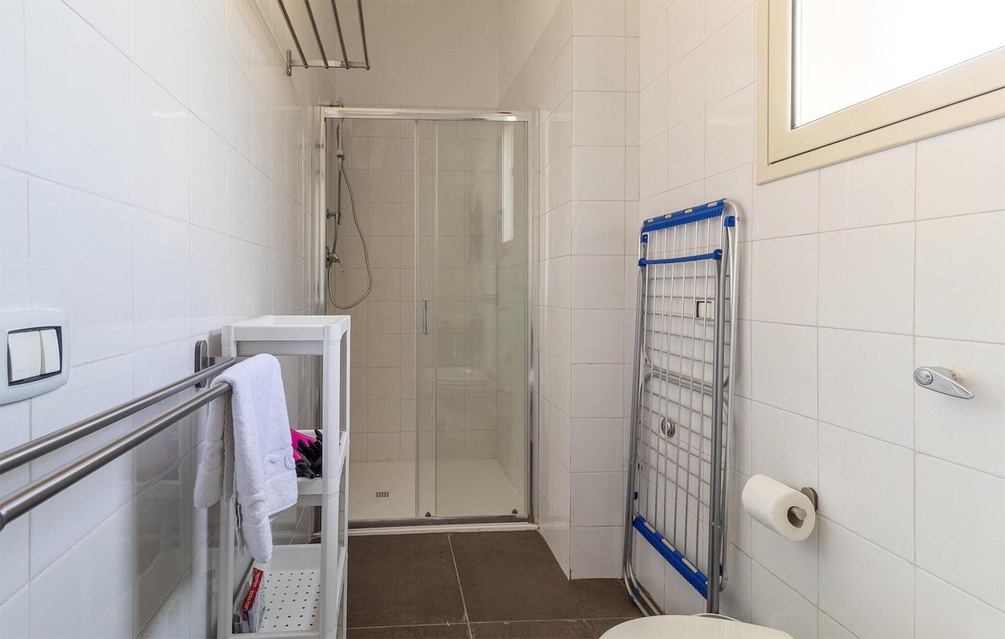 A bathroom with a shower, a towel rack, a toilet, and a paper towel dispenser.