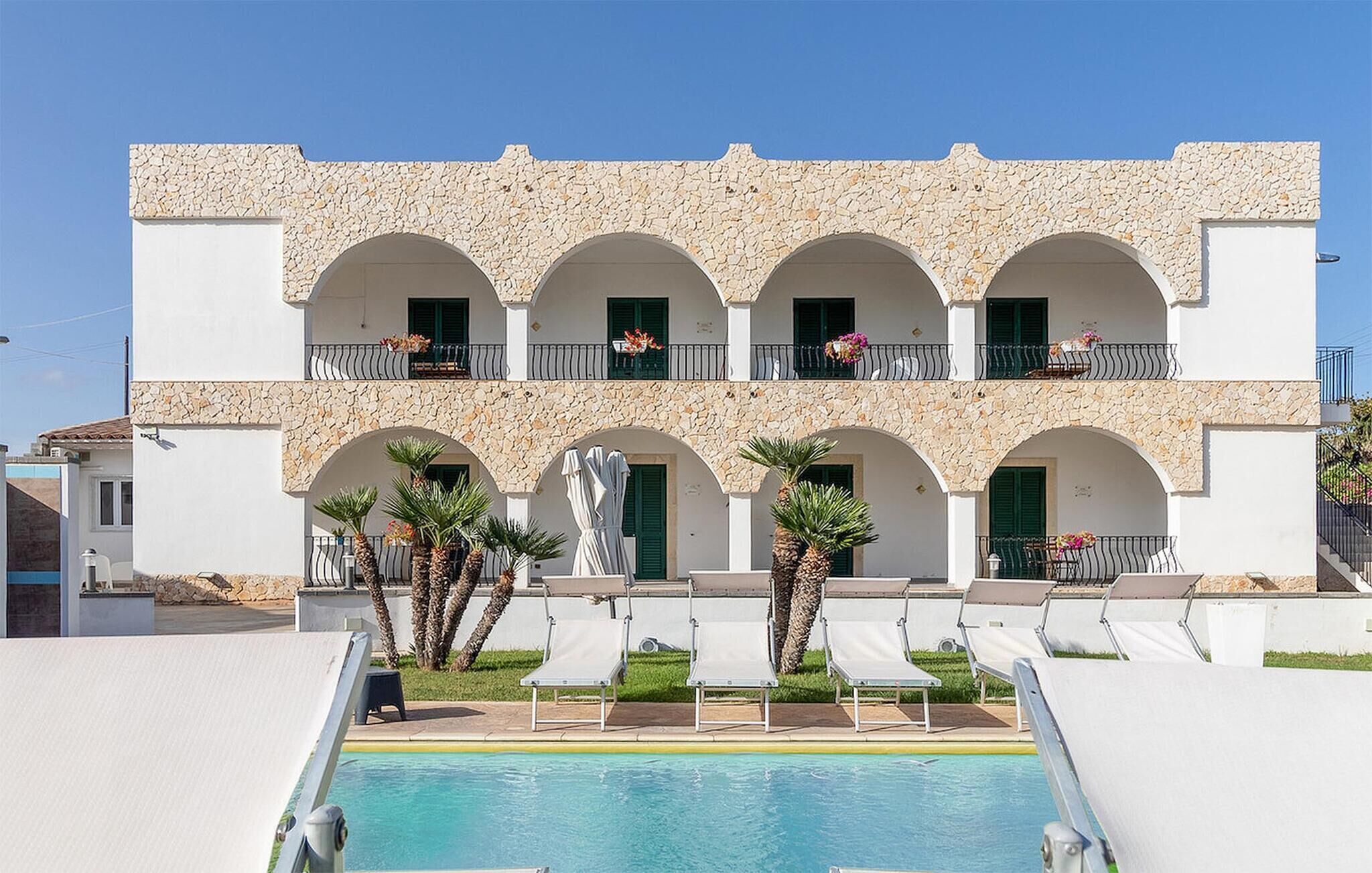 Ein Hotel mit Pool, mehreren Balkonen inklusive Geländer und Außenbereich zum Sitzen.